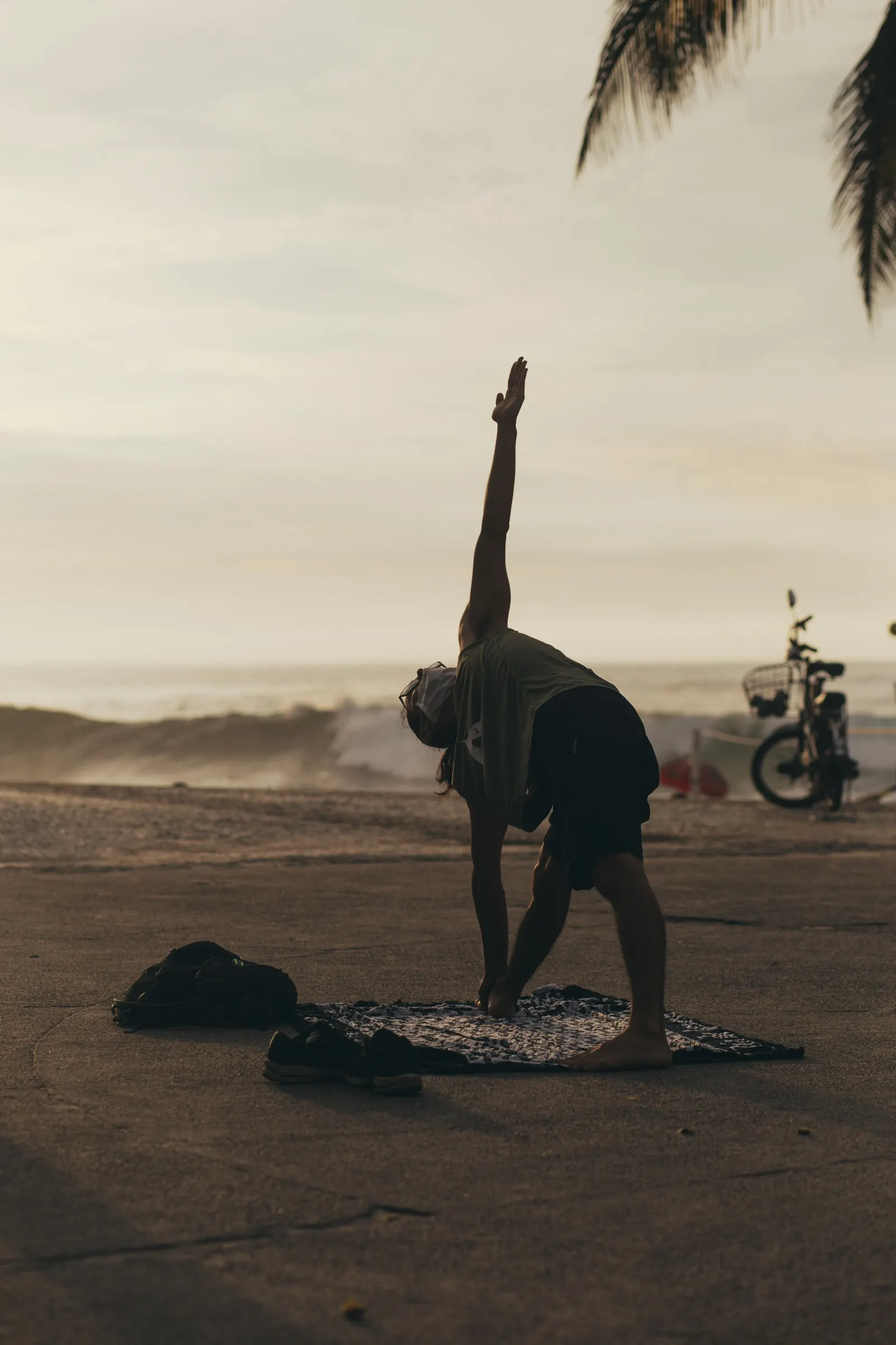 Runner stretching on a beach mat at sunrise